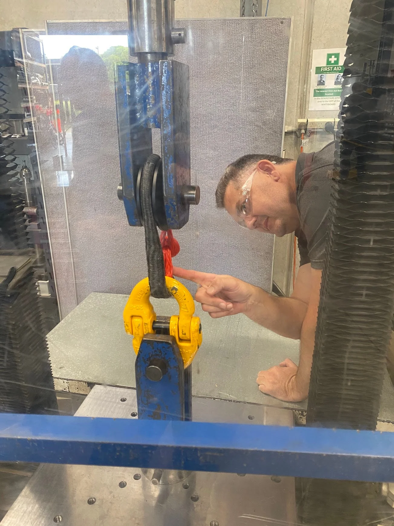 NATA-accredited lab technician inspecting a soft shackle rigged into a hydraulic test frame before a destructive pull test