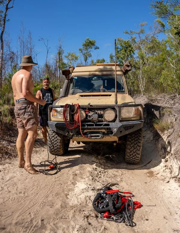 Two 4WD drivers standing beside a Toyota Land Cruiser fitted with a winch and recovery gear on a bush track