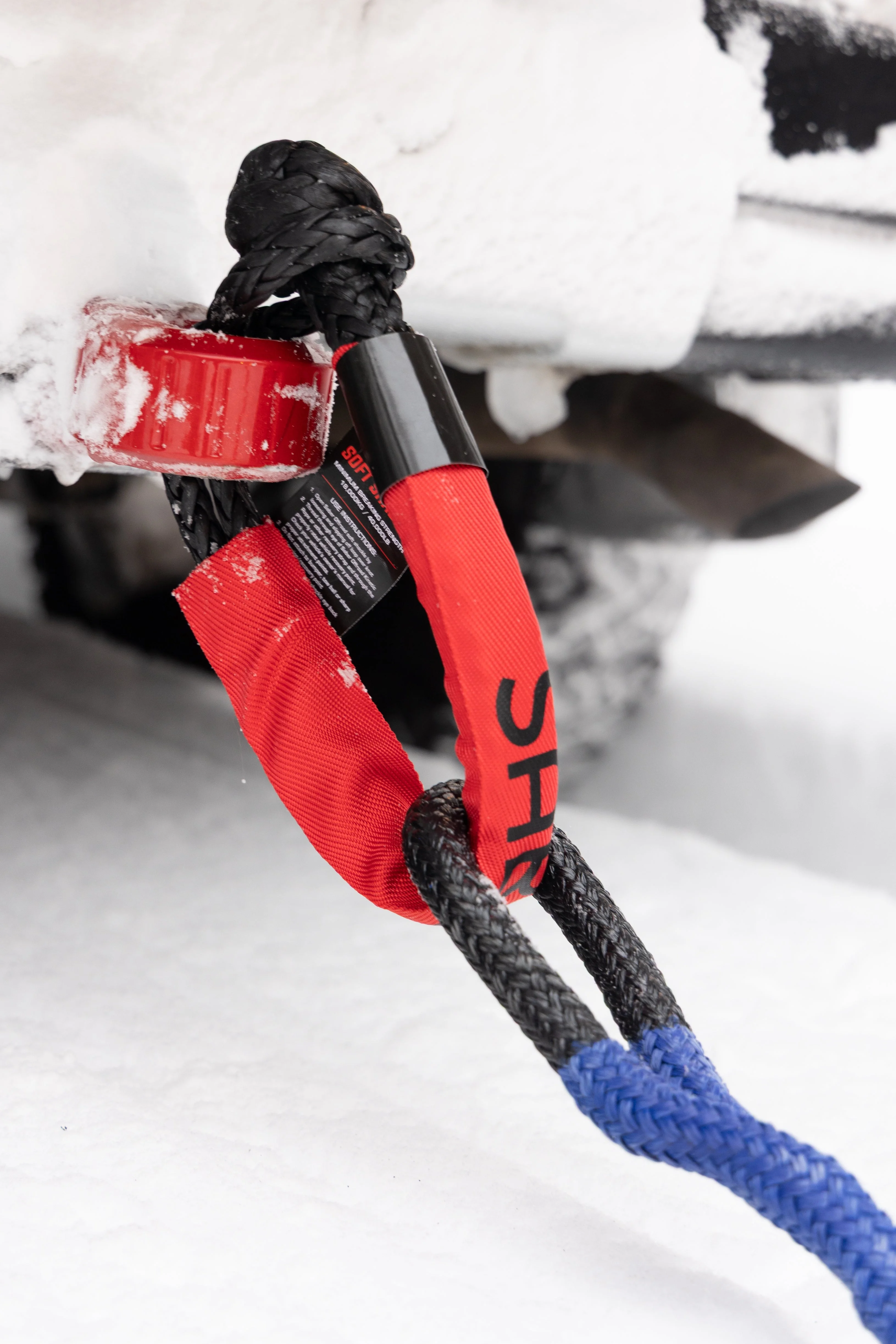 Red Saber soft shackle and blue kinetic rope attached to a snow-covered vehicle's front recovery point